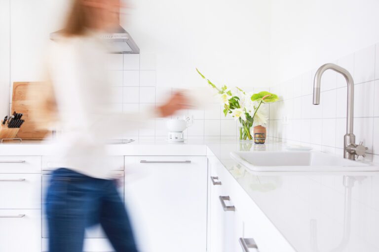 Woman walking in a modern white kitchen. Motion blurred.